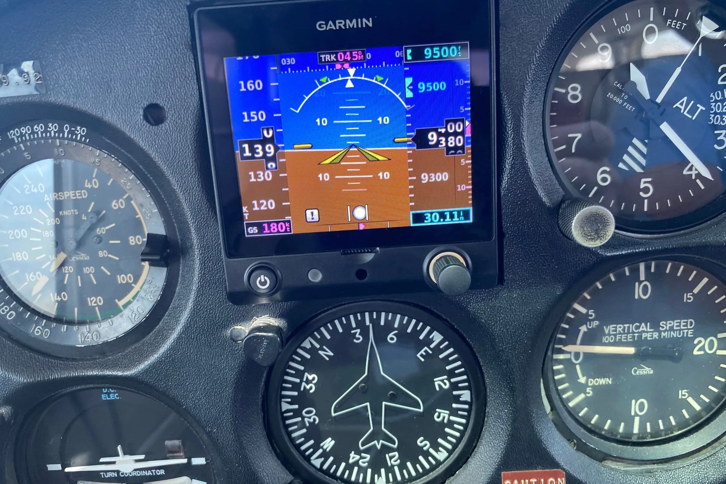 A Garmin G5 attitude display set among round gauges in a light airplane’s instrument panel